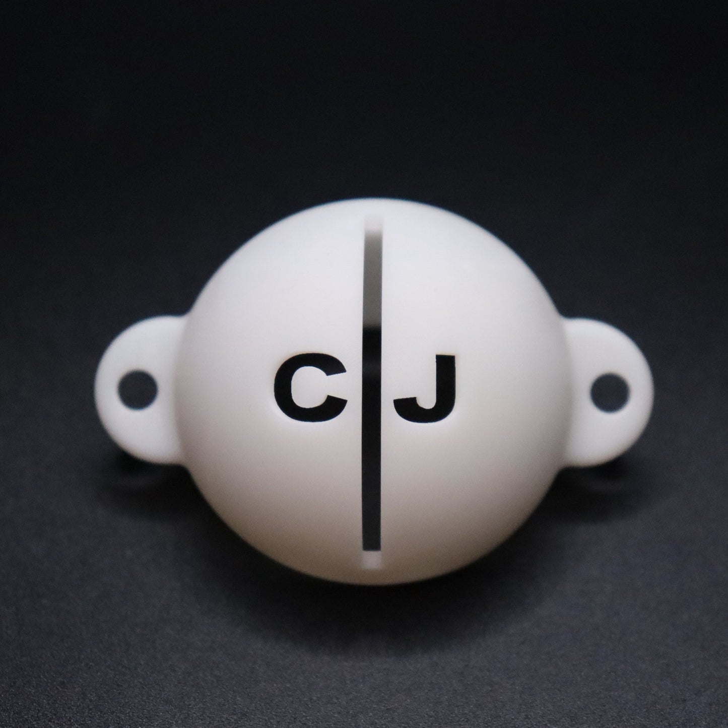 Golf ball marker stencil manufactured via 3D printing in white plastic material. Two letters for initials, one on each side of an alignment line for putting