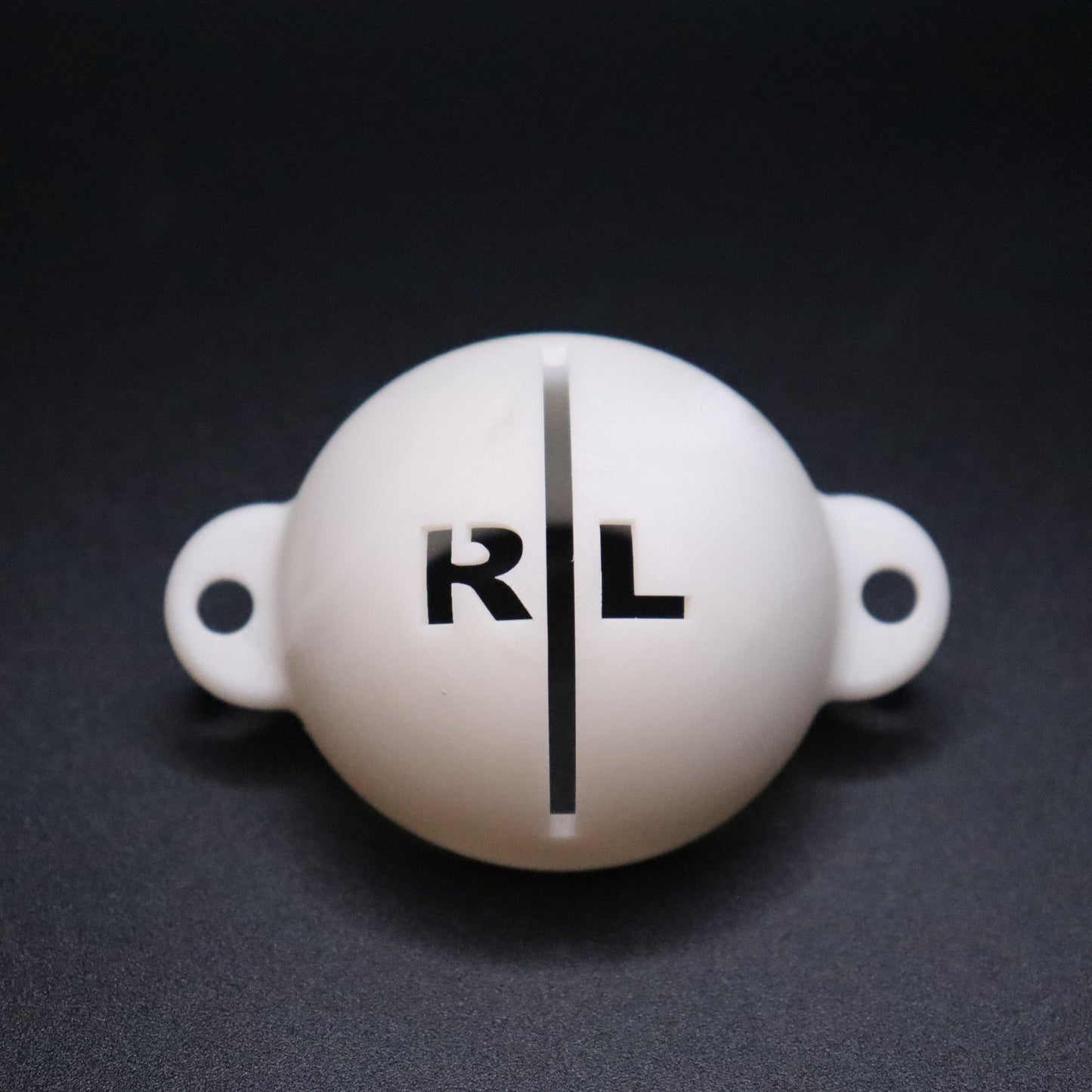 Golf ball marker stencil manufactured via 3D printing in white plastic material. Two letters for initials, one on each side of an alignment line for putting