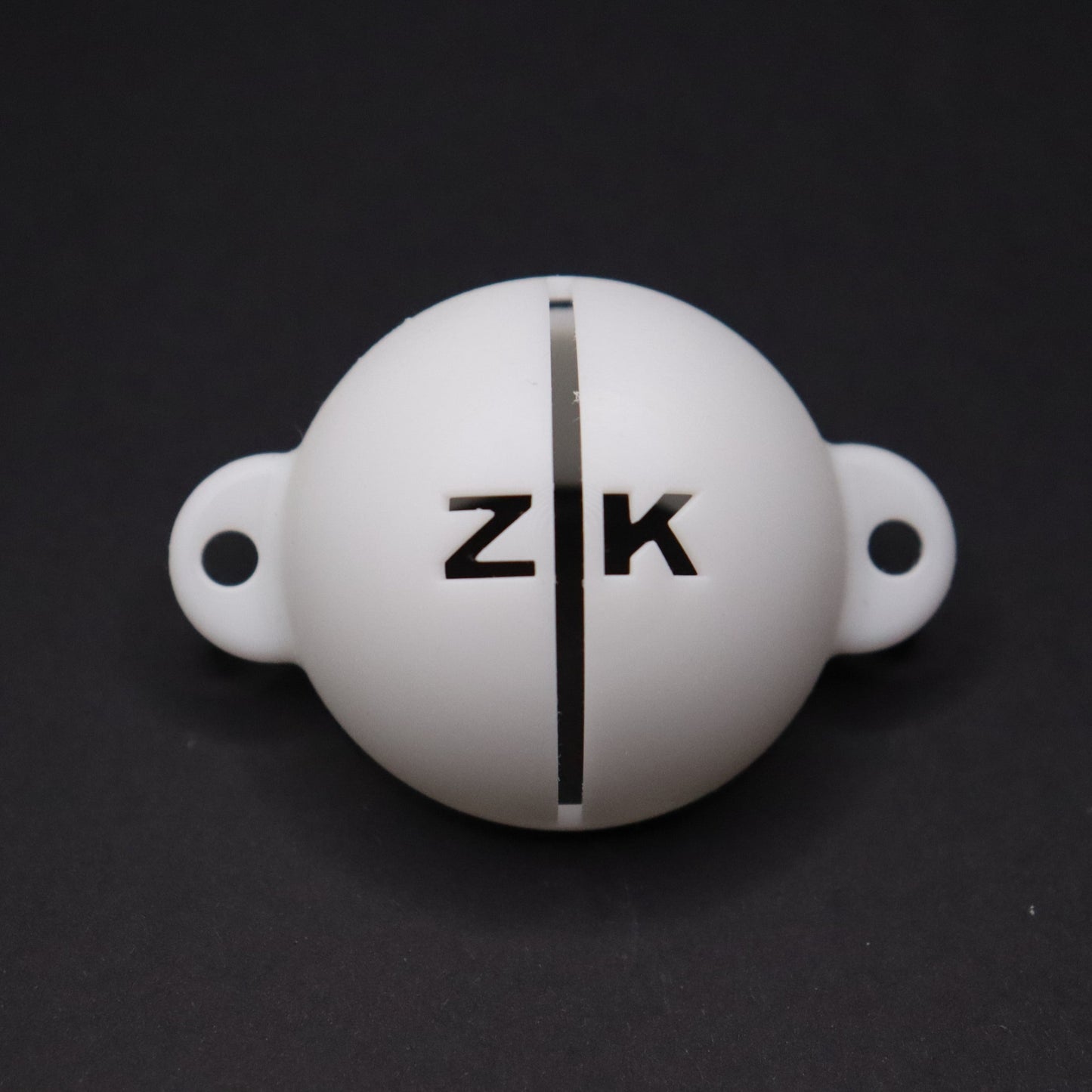 Golf ball marker stencil manufactured via 3D printing in white plastic material. Two letters for initials, one on each side of an alignment line for putting